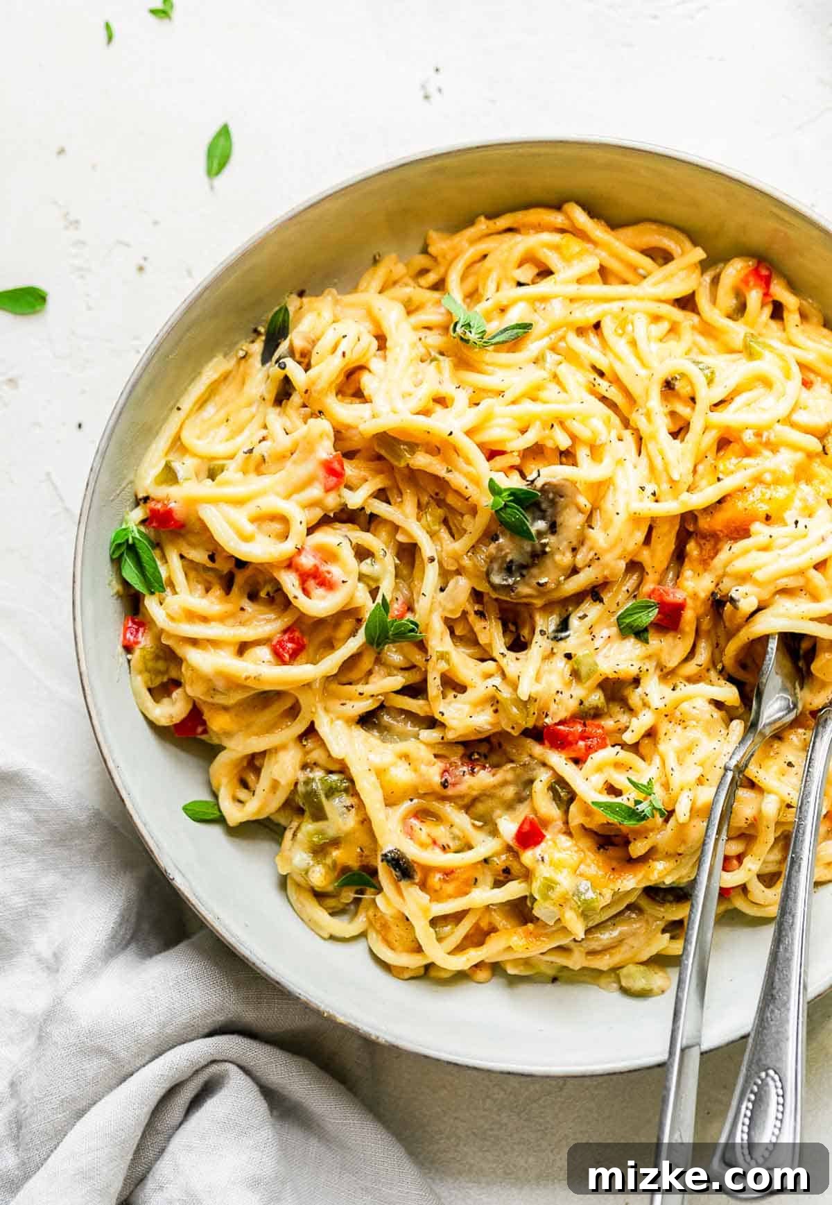 Cheesy Spaghetti Bake 8 Baked spaghetti casserole served in a large bowl with metal serving utensils, ready to be enjoyed.