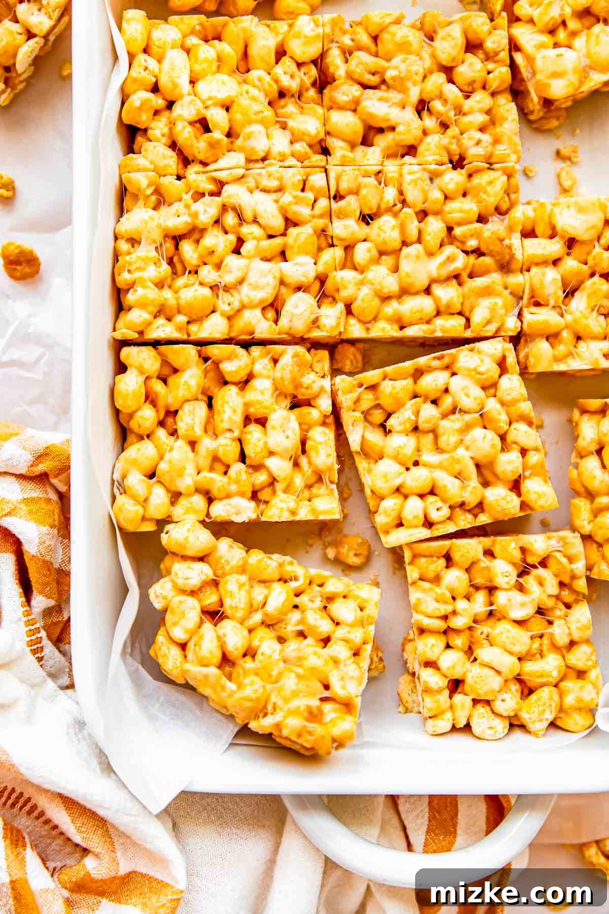 Wholesome Grain Bars 12 Several golden cereal bars are arranged neatly in a white baking dish, showcasing their inviting texture.
