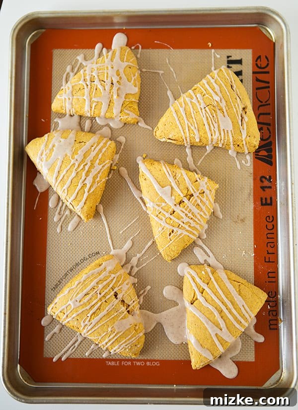 Starbucks Copycat Pumpkin Scones | tablefortwoblog.com Close-up of Starbucks Copycat Pumpkin Scones on a baking sheet, showcasing their texture and spiced glaze