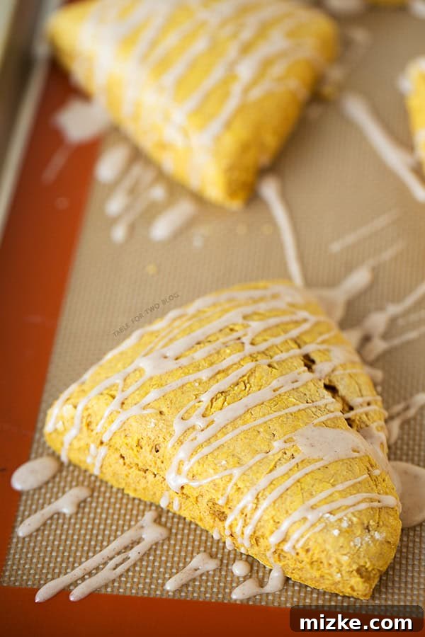 Starbucks Copycat Pumpkin Scones | tablefortwoblog.com A plate of Starbucks Copycat Pumpkin Scones with delicate icing drizzles, ready to be enjoyed
