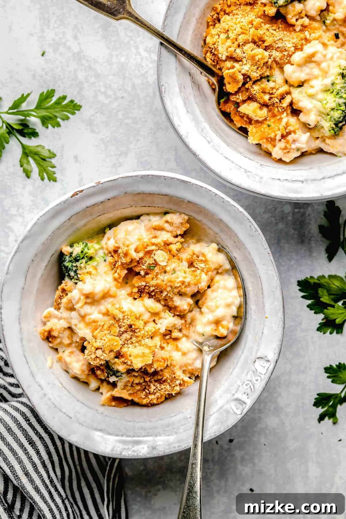 This cheesy chicken broccoli rice casserole is topped with buttery Ritz crackers and comes together so quickly. It's a perfect weeknight meal. Chicken broccoli rice casserole served in bowls with spoons.