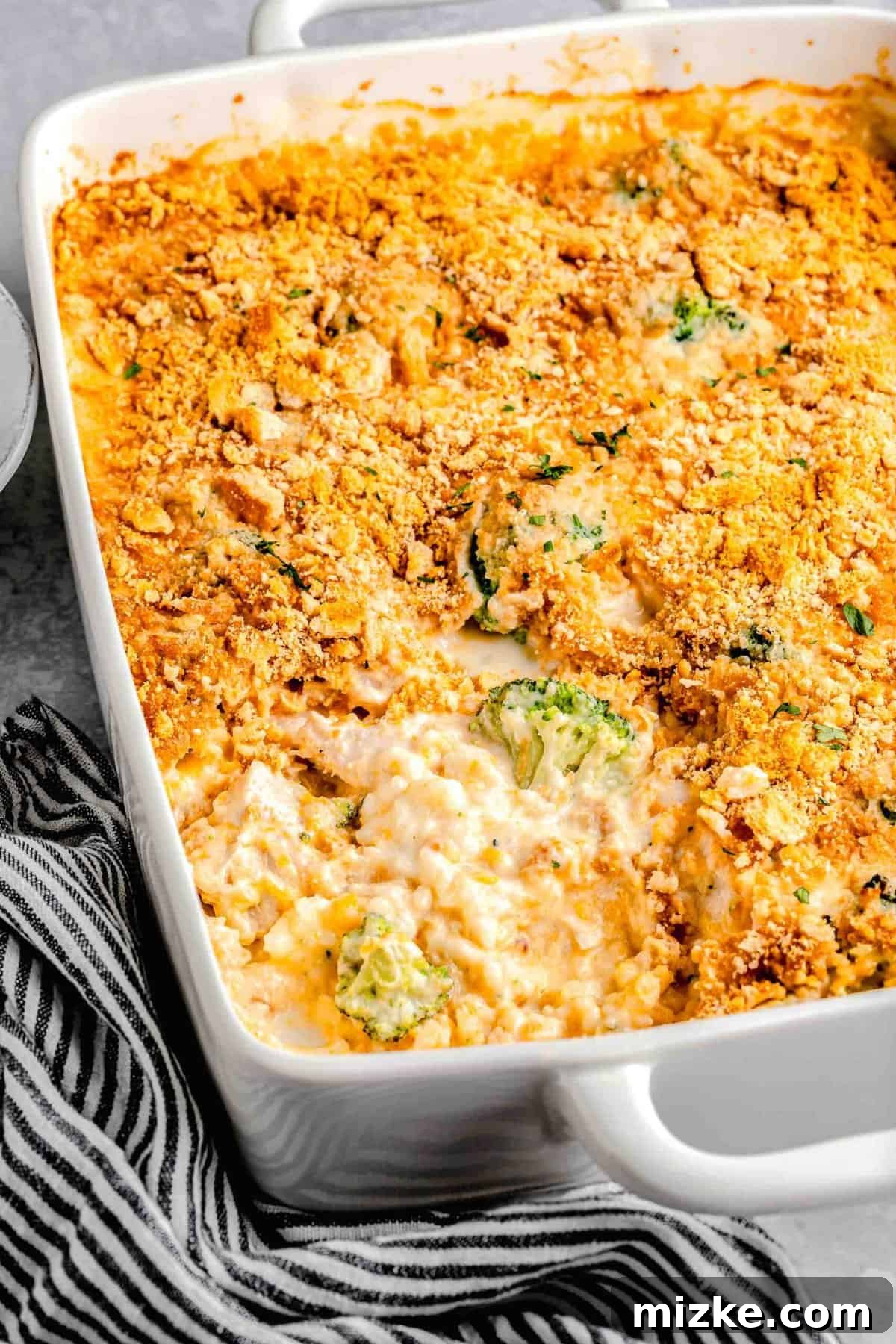 This cheesy chicken broccoli rice casserole is topped with buttery Ritz crackers and comes together so quickly. It's a perfect weeknight meal. Chicken broccoli rice casserole in a casserole dish with a pice taken out of it.