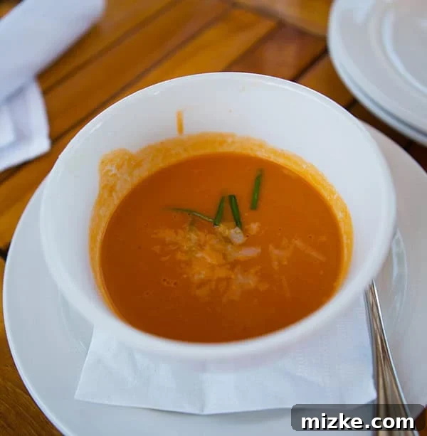 Roasted heirloom tomato soup, a simple yet comforting starter. A bowl of roasted heirloom tomato soup with a garnish.
