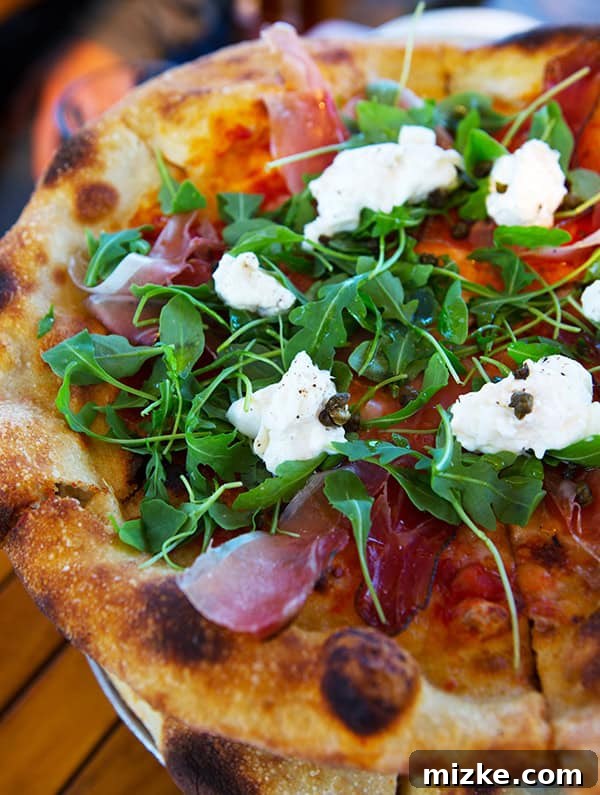 A sensational speck, burrata, and arugula pizza from Bar Bocce. A gourmet pizza topped with speck, burrata cheese, and fresh arugula.