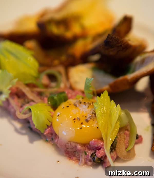 Kobe tartare: A fresh and luxurious appetizer. Finely chopped Kobe beef tartare with an egg yolk on top, garnished with herbs.