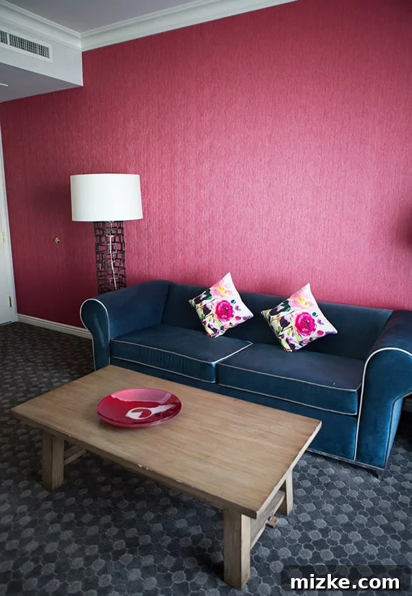 The beautifully appointed living area of a Kimpton Hotel Monaco suite. A luxurious hotel suite living room with rose-colored walls and elegant furniture.