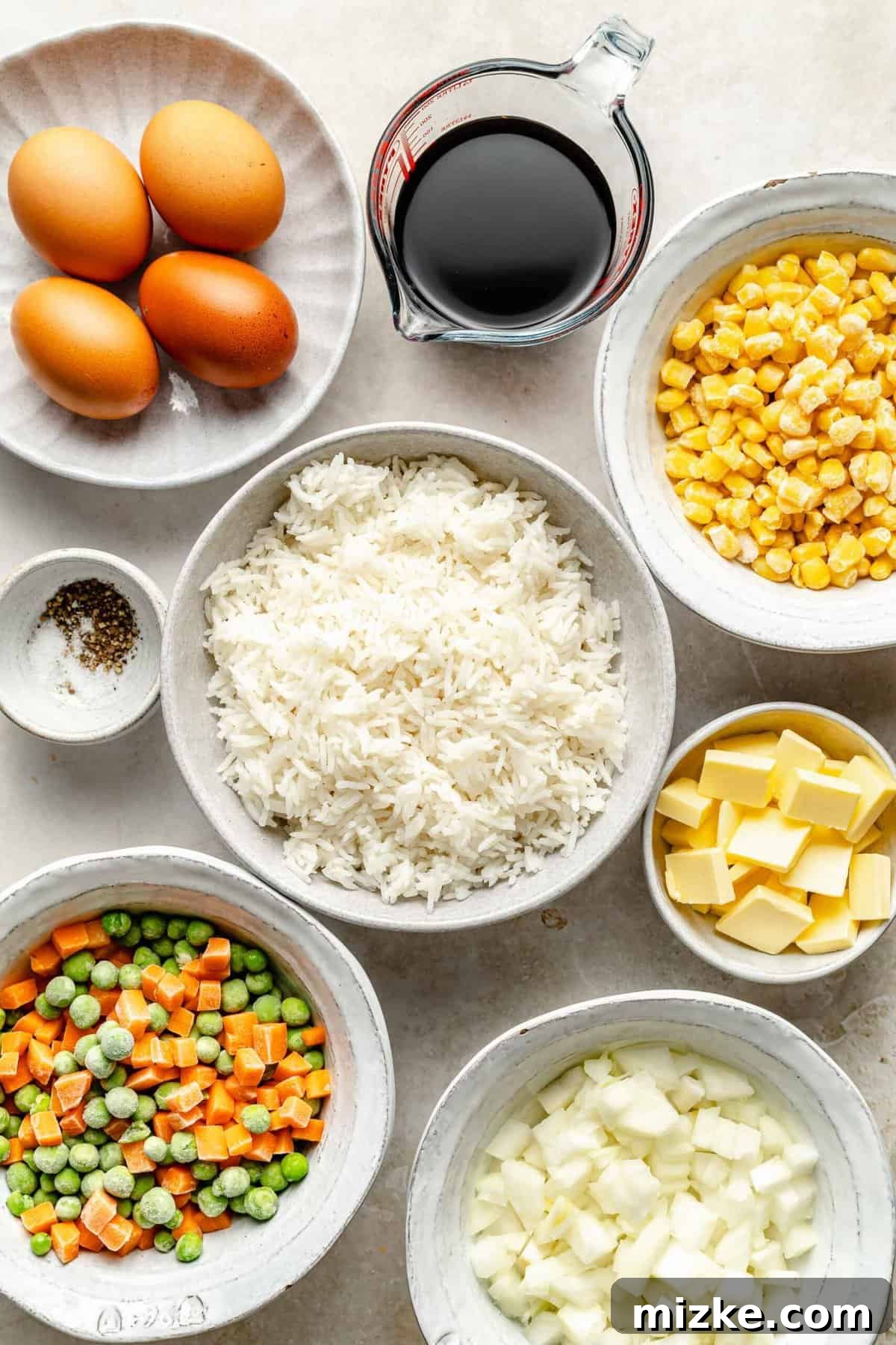 Fresh ingredients ready for delicious homemade fried rice. All fresh ingredients neatly arranged for making vegetable fried rice, including rice, eggs, butter, and various vegetables.