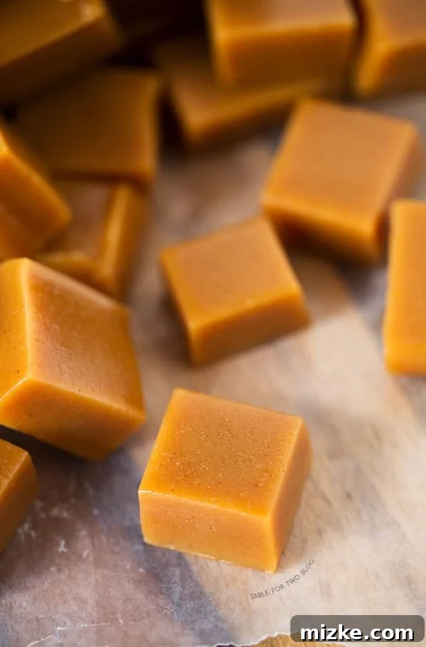 A close-up view of a wrapped apple cider caramel, showing the traditional twist of wax paper, ready for gifting or savoring.