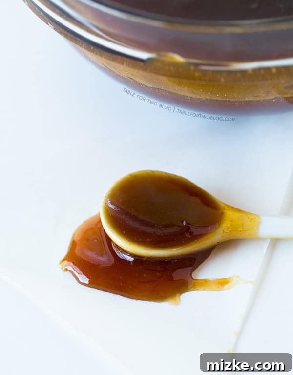 Boiled Cider | tablefortwoblog.com Boiled Cider drizzled over a spoon, demonstrating its thick, viscous consistency.