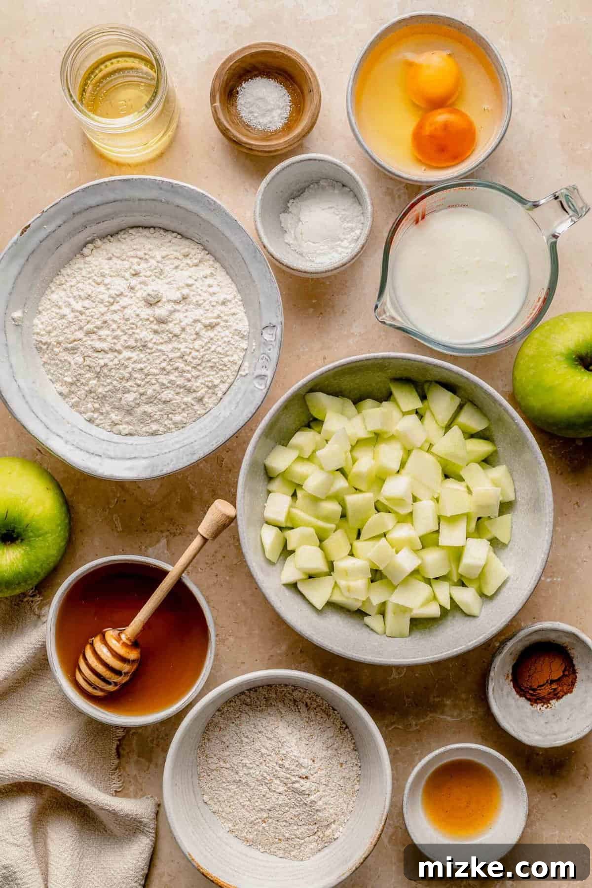 These moist, tender apple cinnamon muffins are filled with an abundance of apples and a heartwarming combination of honey and cinnamon. Ingredients for apple cinnamon muffins separated into bowls.