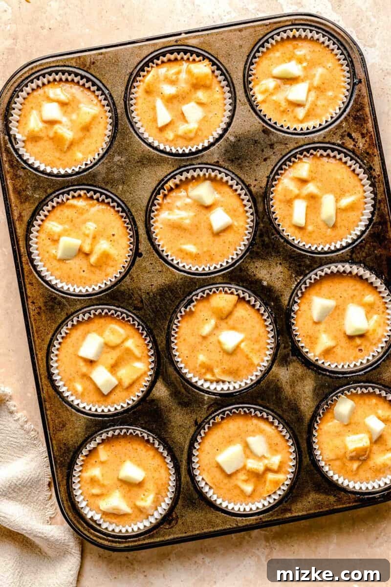 These moist, tender apple cinnamon muffins are filled with an abundance of apples and a heartwarming combination of honey and cinnamon. Muffin tins filled with cinnamon apple muffin batter.