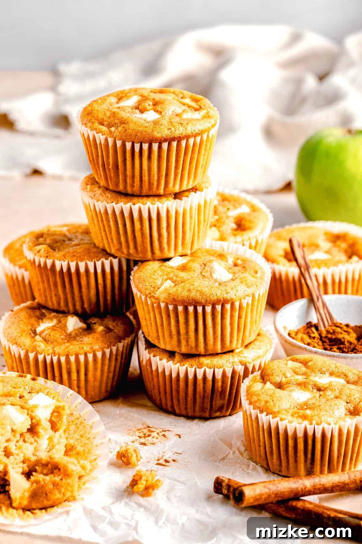 These moist, tender apple cinnamon muffins are filled with an abundance of apples and a heartwarming combination of honey and cinnamon. A stack of apple cinnamon muffins.
