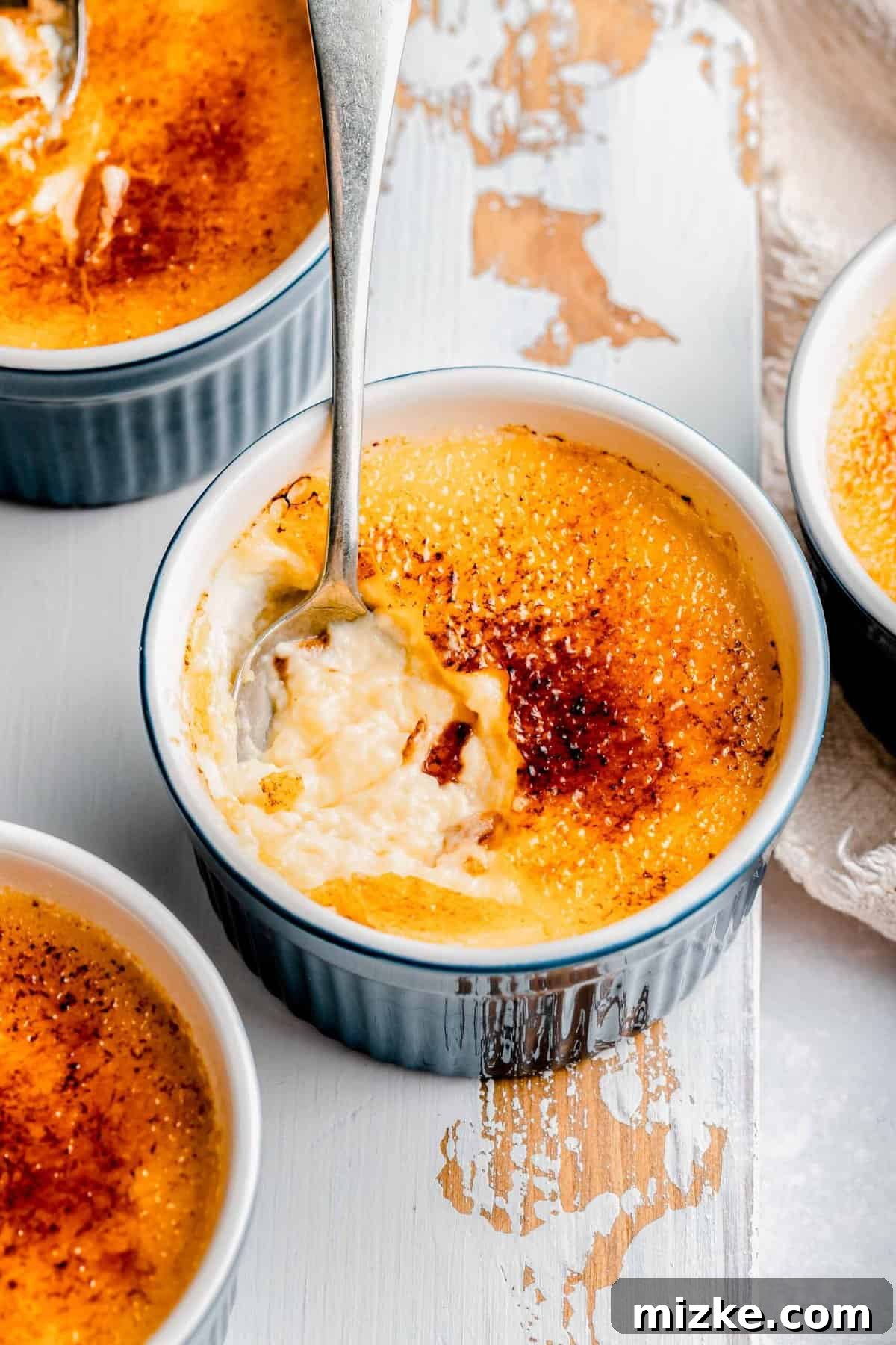 Indulge in a spoonful of creamy homemade crème brûlée with a perfectly torched sugar crust. Digging a spoon into homemade creme brulee, showing the creamy custard beneath a golden, crisp sugar crust.