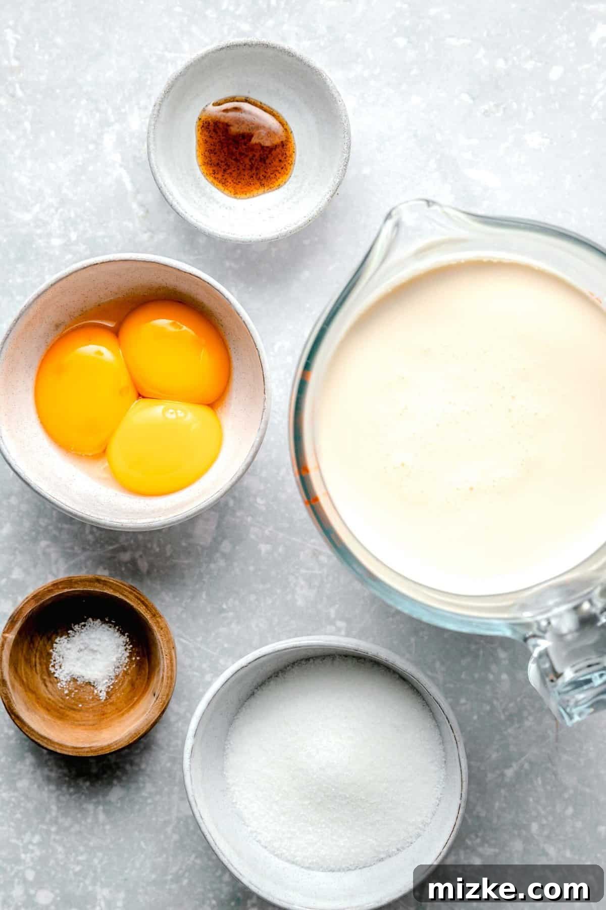 Simple ingredients for an extraordinary homemade crème brûlée. Basic ingredients for making homemade creme brulee laid out on a table: heavy cream, vanilla bean paste, eggs, sugar, and salt.