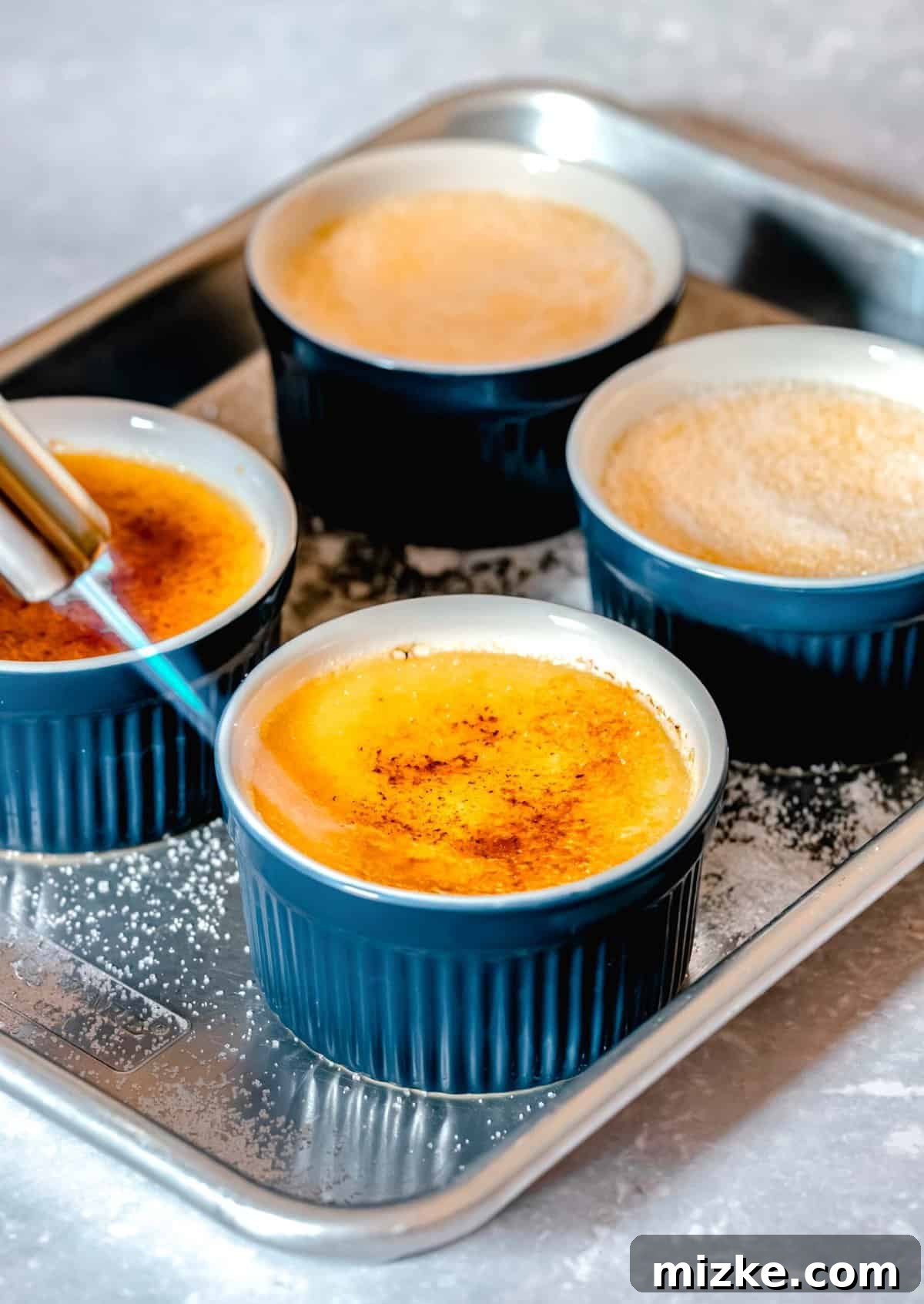 Caramelize the sugar topping with a culinary torch for the perfect crisp crust. A culinary torch being used to caramelize sugar sprinkled over creme brulee in ramekins, creating a crisp golden topping.