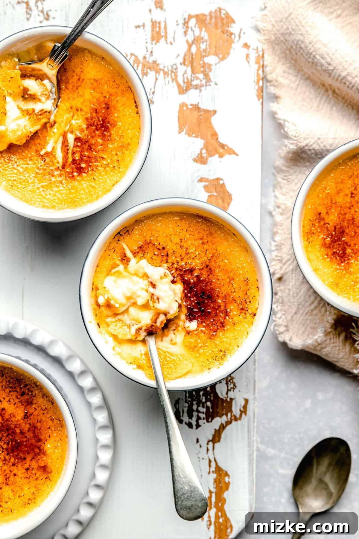 A close-up of delicious homemade crème brûlée, ready to be devoured. Closeup overhead shot of ramekins filled with crème brûlée, some with spoons, showing the inviting texture.
