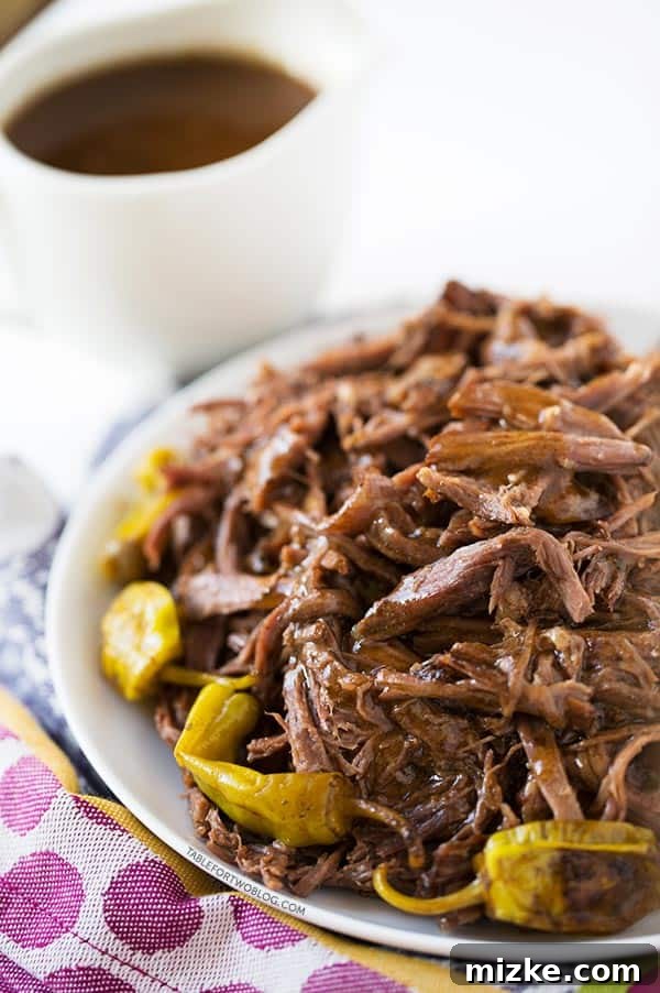 This Mississippi Roast recipe is your ticket to a delicious, no-fuss slow cooker meal. With just five ingredients, it promises tender beef and amazing flavor for dinner and beyond. A vibrant and inviting Mississippi Roast, complete with pepperoncini, is elegantly plated on a white dish atop a purple polka-dotted towel, with a rich gravy boat waiting in the background, ready to elevate the meal.