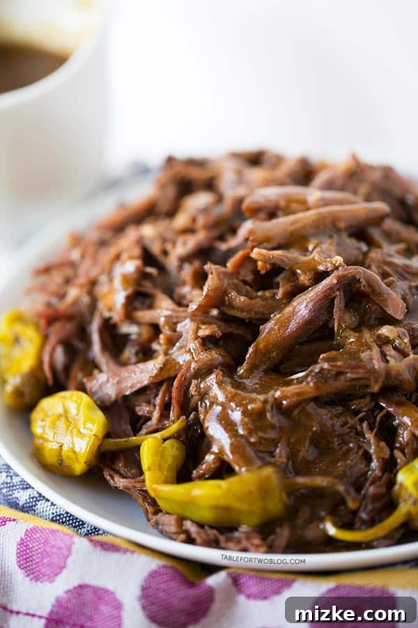 Savor the succulent tenderness of Mississippi Roast, slow-cooked to perfection with a tangy, savory au jus and vibrant pepperoncini. A truly satisfying meal for any occasion. A stunning close-up of Mississippi Roast, rich with savory au jus, presented on a white plate with zesty pepperoncini. The plate is thoughtfully placed on a charming purple polka-dotted towel, highlighting the dish's irresistible appeal.
