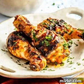 20 Quick Chicken Dinners for Busy Weeknight Meals 17 Grilled chicken drumsticks garnished with herbs on a white plate, with a side of corn and a bowl of rice in the background.