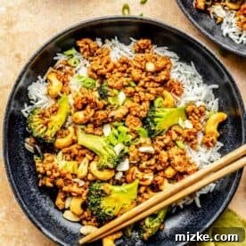20 Quick Chicken Dinners for Busy Weeknight Meals 7 cashew chicken and broccoli in a black bowl with white rice next to wooden chopsticks