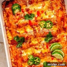 beef enchiladas in a baking dish topped with cilantro, jalapeños and lime slices