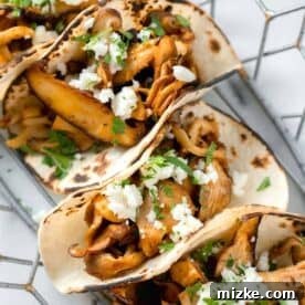 oyster mushroom tacos stacked in a wire basket with fresh parsley and cotija cheese garnished on top