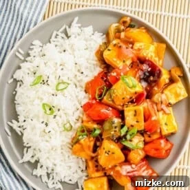 tofu, veggies, and rice are presented together on a single round plate.
