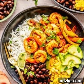 shrimp bowls plated in black bowls with a gold fork with shrimp and bell peppers on top of white rice