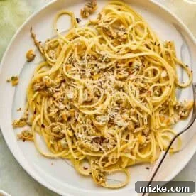 A plate of linguine with clams, garnished with grated cheese and red pepper flakes, accompanied by a fork.